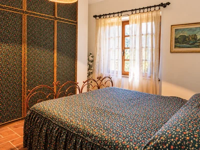 A bright bedroom with patterned curtains and wooden furniture