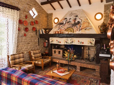 A stone living room with a fireplace, wooden beams and cosy seating