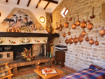 A masonry fireplace and copper pans hanging on a stone wall