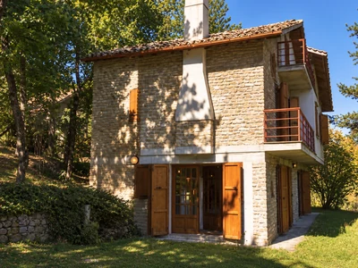 The stone façade of Casa dello Scoiattolo, surrounded by trees