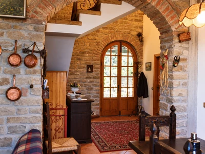 An entrance with stone walls, an arched wooden doorway and a rug