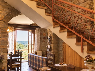 A wooden staircase with an iron railing and a window looking out onto greenery